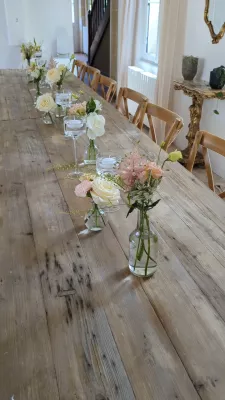 Centre de table champêtre élégant pour mariage, avec roses crème et astilbe rose, feuillage varié sur table en bois.
