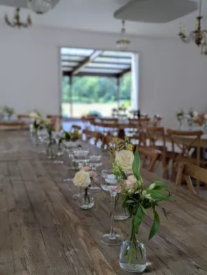 Centre de table champêtre élégant pour mariage, avec roses crème et astilbe rose, feuillage varié sur table en bois.