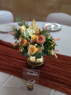 Centre de table bohème avec roses pêche, chrysanthèmes et éléments séchés pour un mariage à Château La Caussade.