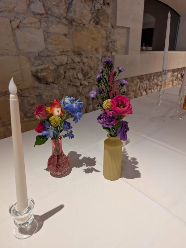 Sophisticated country-style table centrepiece featuring fuchsia roses, blue delphiniums and purple scabiosas for a wedding.