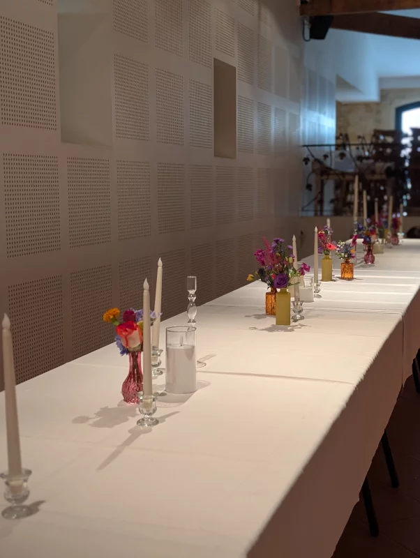 Long wedding table with sophisticated rustic table centrepieces, roses, delphiniums and candles.