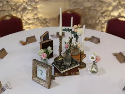 Centre de table bohème avec petites roses, gypsophile, eucalyptus, livres anciens, bougies et chandeliers laiton.