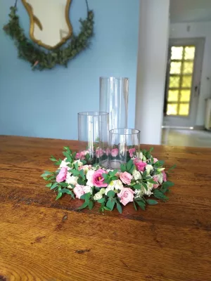 Centre de table champêtre élégant avec roses roses et blanches, eucalyptus, entourant trois vases en verre transparent pour un mariage.