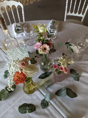 Centres de table champêtres avec roses, gerberas roses, œillets corail et eucalyptus pour une réception de mariage.