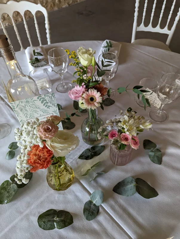 Rustic table centrepieces featuring roses, pink gerberas, coral carnations and eucalyptus for a wedding reception.