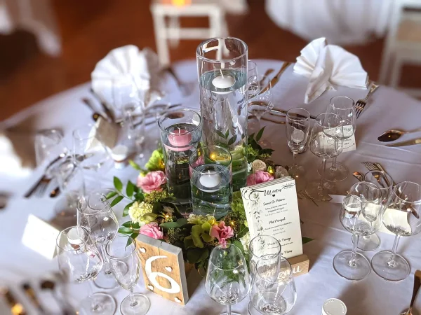 Centre de table de mariage champêtre avec roses roses, lisianthus blancs et feuillage vert.