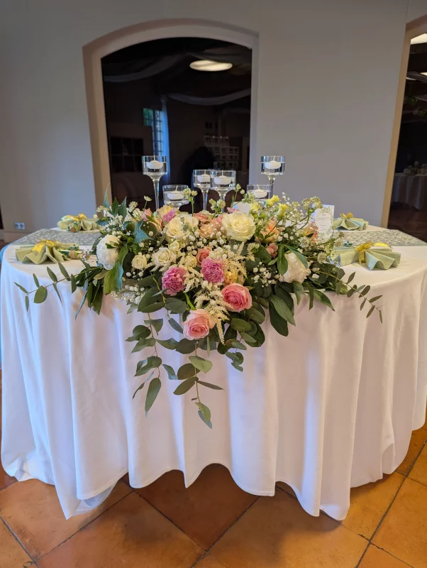 Centre de table champêtre sophistiqué avec roses, lisianthus et eucalyptus pour table d'honneur.