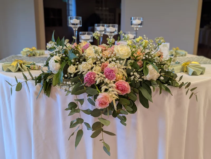 Sophisticated rustic table centrepiece with roses, lisianthus and eucalyptus, close-up view.