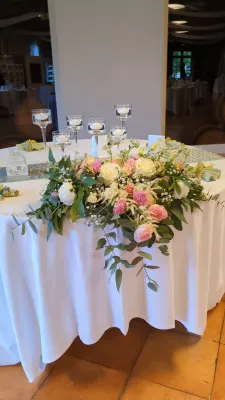 Centre de table champêtre sophistiqué avec roses, lisianthus et eucalyptus pour table d'honneur.