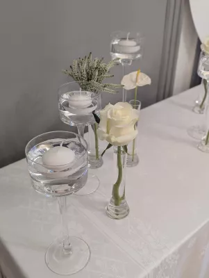 Minimalist table decoration with floating white roses and candles for a wedding.