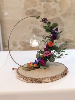 Centre de table original avec roses orange, violettes, eucalyptus et bougie suspendue.