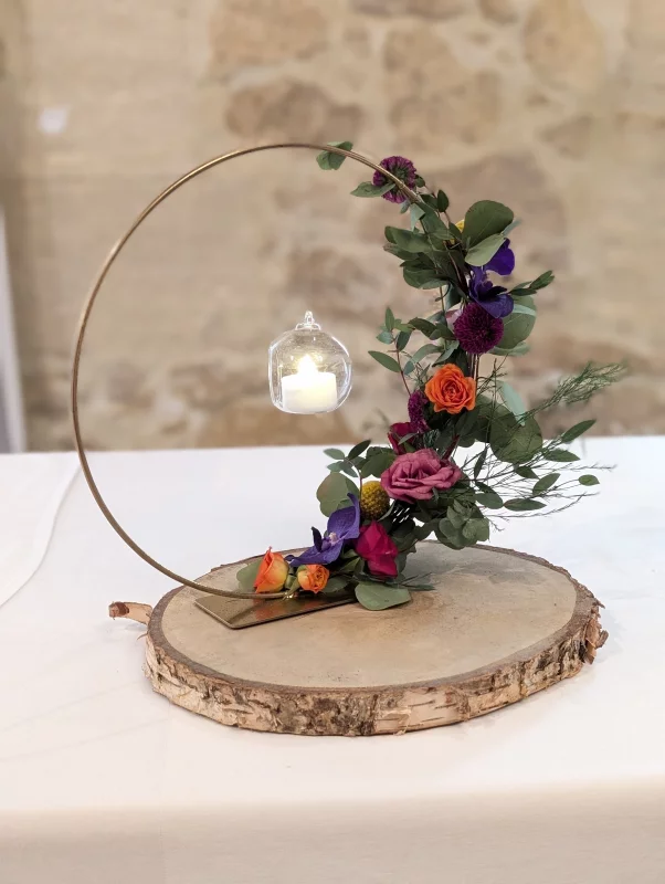 Unique table centrepiece with orange roses, violets, eucalyptus and a suspended candle.
