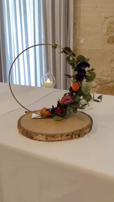 Unique table centrepiece with orange roses, purple blooms, eucalyptus and a hanging candle.