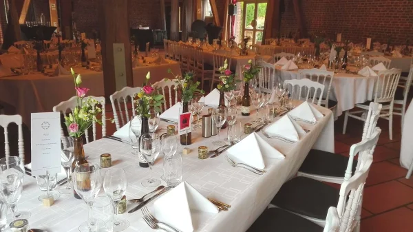 Centre de table de mariage classique, avec des roses roses claires et fuchsia, du feuillage vert et des petites fleurs blanches.