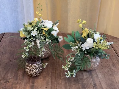 Rustic-bohemian table centrepieces for a winter wedding, adorned with white roses, yellow flowers, and assorted ferns.