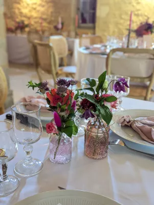 Small table centrepieces with pink roses and purple fritillaries in textured vases, sophisticated country style.