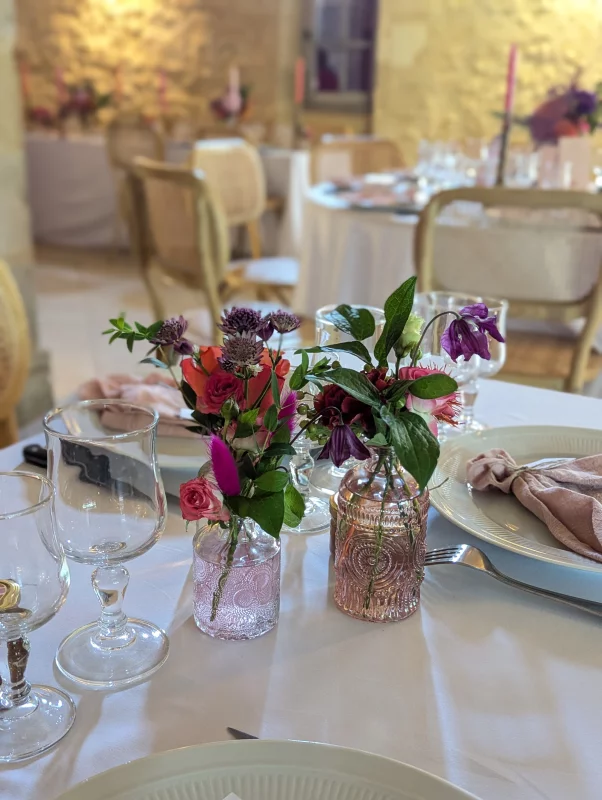 Small table centrepieces with pink roses and purple fritillaries in textured vases, sophisticated country style.