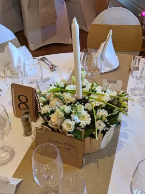 Gros plan sur un élégant centre de table de mariage, mélangeant roses, gerberas et arums blancs dans un style classique printanier.