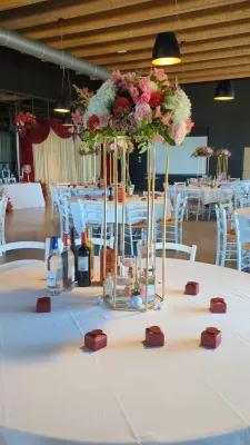 Sophisticated country-style table centrepiece with roses, white hydrangeas, and pink alstroemerias for a wedding.