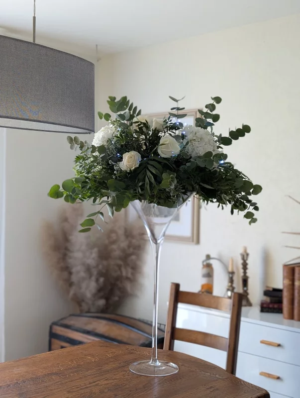 Centre de table classique avec roses blanches, hortensias et eucalyptus, composition florale élégante pour mariage