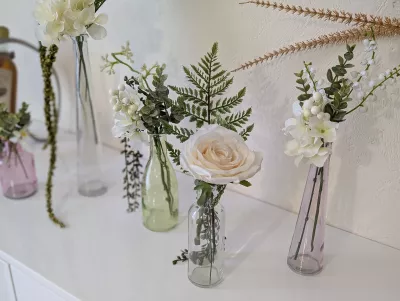 Centre de table élégant et classique pour mariage d'hiver avec roses blanches, hortensias et feuillage vert dans des vases en verre.