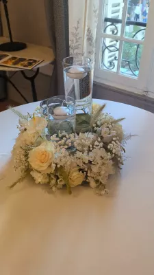 Romantic organic table centrepiece with cream roses, white hydrangeas, and floating candles, Château des Eyres wedding.