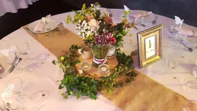 Centre de table champêtre élégant pour mariage, avec roses crème, lierre verdoyant et délicates fleurs des champs.