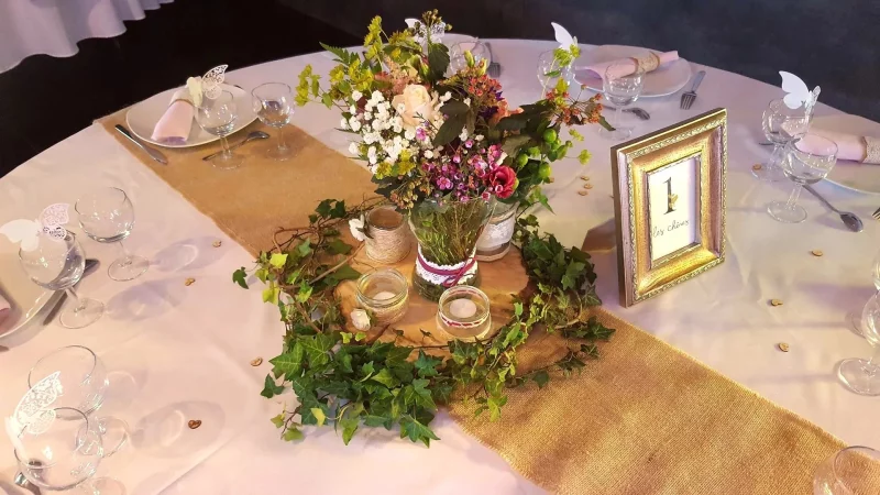 Centre de table champêtre élégant pour mariage, avec roses crème, lierre verdoyant et délicates fleurs des champs.