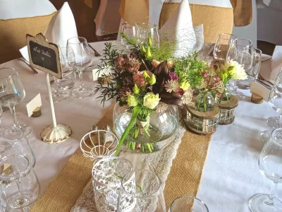 Centre de table mariage champêtre avec roses, lisianthus, feuillages variés et petites fleurs pourpres.