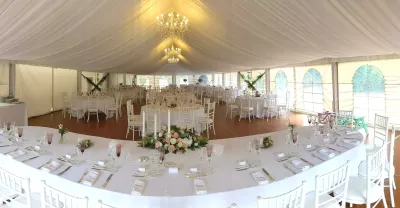 Vue panoramique d'une salle de réception de mariage avec centre de table classique de roses, lisianthus et feuillage.