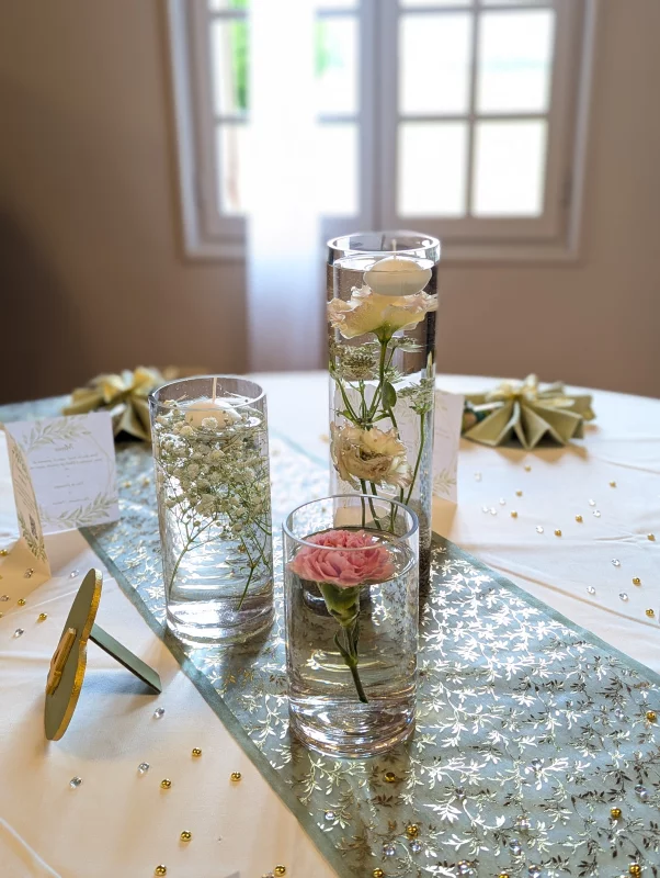 Centres de table minimalistes avec roses, lisianthus et gypsophile dans des vases en verre.