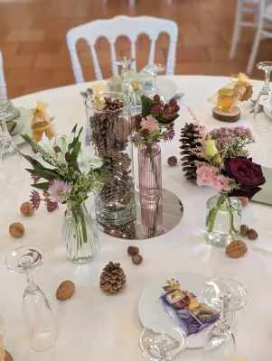 Detail of sophisticated rustic table centrepiece with burgundy roses, pink carnations, and foliage