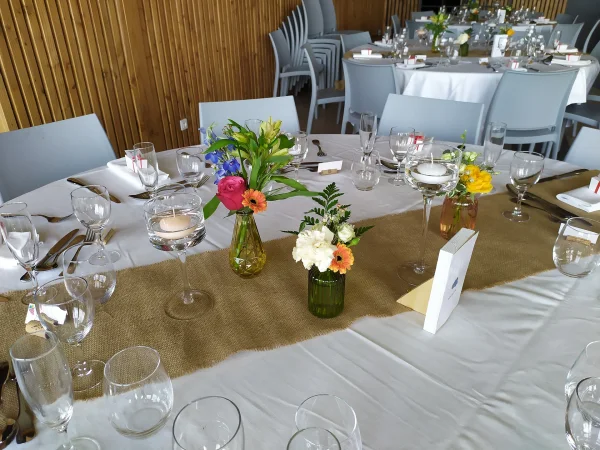 Centres de table champêtres avec roses, alstroemeria et fougère, vases colorés pour mariage Jennifer.