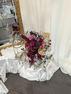 Centre de table de mariage classique avec roses bordeaux, anthuriums dorés et orchidées magenta, agrémenté d'un chandelier en cristal.