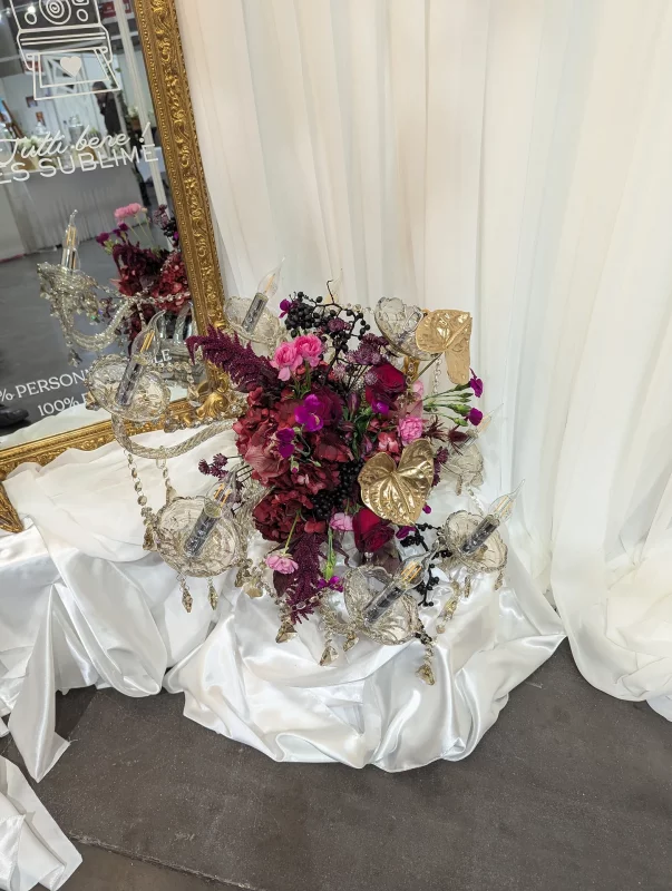 Classic wedding table centrepiece featuring burgundy roses, golden anthuriums, and magenta orchids, adorned with a crystal chandelier.
