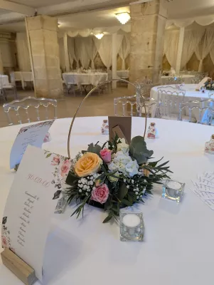Centre de table élégant dans un cercle doré avec roses pêche, roses poudré et hortensias blancs pour un mariage.