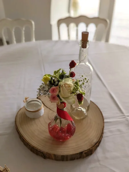 Centre de table champetre avec roses roses, gypsophile et baies rouges pour un mariage en ete au Domaine De Larchey.