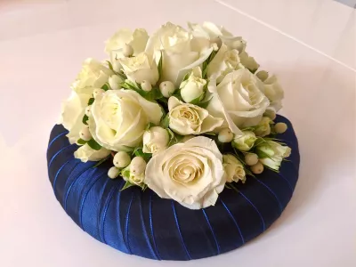 Classic wedding table centrepiece, featuring creamy white roses and delicate pale berries on a blue base.
