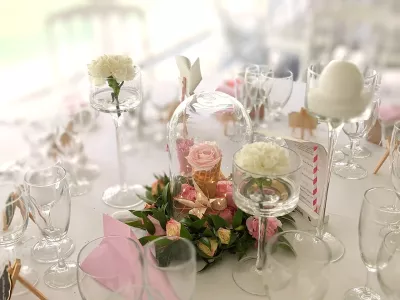 Centre de table classique avec composition de roses roses, jaunes, carnations sous cloche en verre pour mariage.