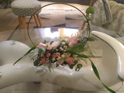Centre de table rond avec roses poudrées, gypsophile et eucalyptus, style champêtre romantique pour un mariage.