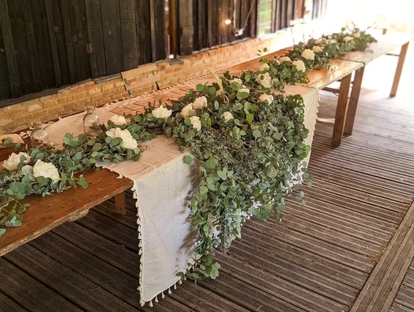 Magnifique centre de table champêtre pour mariage avec roses blanches et eucalyptus, créant une atmosphère douce et naturelle.