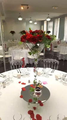 Grand centre de table classique avec un opulent arrangement de roses rouges et de lys dans un vase martini, mariage.