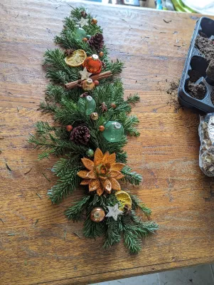 Woodland-inspired Table Centrepiece for a Winter Wedding, with fir branches, dried orange slices and pine cones.