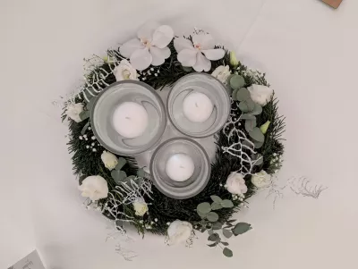 Centre de table classique avec couronne de sapin, orchidées blanches, roses et bougies flottantes pour un mariage d'hiver.