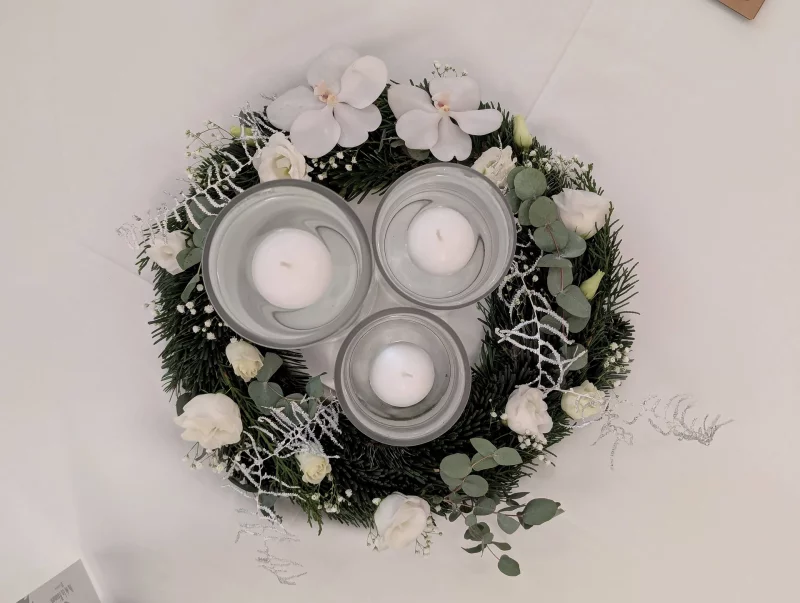 Centre de table classique avec couronne de sapin, orchidées blanches, roses et bougies flottantes pour un mariage d'hiver.