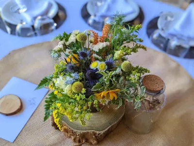 Centre de table champêtre avec tournesols, chardons et amarante pour un mariage à Saint-Côme.
