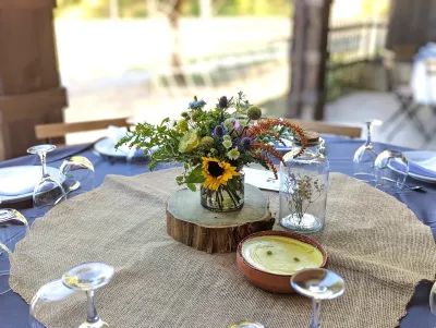 Composition florale champêtre avec tournesol et chardons, décorant une table de mariage.