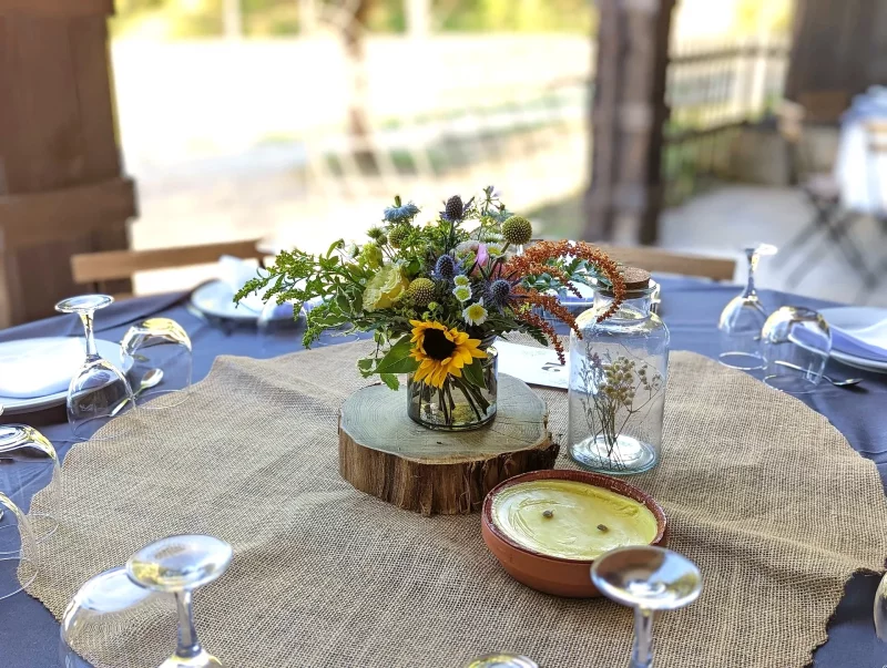 Country-style floral arrangement featuring sunflowers and thistles, adorning a wedding table.