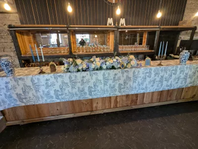 Longue composition florale classique pour buffet avec roses crème, hortensias bleus et delphiniums bleus.
