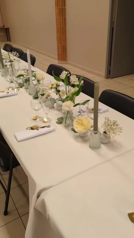 Décoration de centre de table classique pour un mariage, avec roses crème, gypsophile et verdure élégamment disposés.